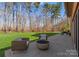 Cozy outdoor seating area with a modern fire pit and serene view of the lush, green backyard and tall trees at 16455 Harbor View Rd, Charlotte, NC 28278