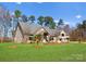 Expansive brick home featuring mature trees, a metal roof, and a well manicured lawn under a bright blue sky at 16455 Harbor View Rd, Charlotte, NC 28278