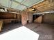 Unfinished garage features brick wall, fireplace, and exposed ceiling at 300 Mcalway Rd, Charlotte, NC 28211
