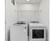 A bright laundry room features a white washer and dryer and wire shelving above at 4114 Rutgers Ave, Charlotte, NC 28206