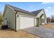 Green home with a two-car garage, black roof, and a newly paved driveway at 501 Everette St, Monroe, NC 28112