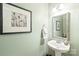 Charming powder room featuring a pedestal sink, decorative mirror, and classic sconce lighting at 6141 Abergele Ln, Matthews, NC 28104