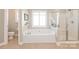 Bright bathroom featuring a large soaking tub, glass shower, and neutral tile at 6141 Abergele Ln, Matthews, NC 28104