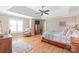 Bright bedroom with hardwood floors, a trey ceiling, ceiling fan, and a cozy sitting area at 6141 Abergele Ln, Matthews, NC 28104