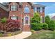 Striking brick home featuring a prominent entryway with a red door and manicured landscaping at 6141 Abergele Ln, Matthews, NC 28104