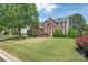 Classic brick home with symmetrical design, manicured landscaping, and a vibrant red front door at 6141 Abergele Ln, Matthews, NC 28104