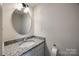 Bathroom with granite countertop, white sink, and round mirror at 6374 Windsor Gate Ln, Charlotte, NC 28215