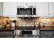 Close up of the kitchen with stainless steel microwave, granite countertops, tile backsplash, and gray cabinets at 667 Portside Dr, Davidson, NC 28036