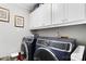 Convenient laundry room featuring modern side-by-side washer and dryer, with overhead storage cabinets at 667 Portside Dr, Davidson, NC 28036