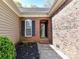 Close-up of brick entryway with black door, trim, and manicured shrubbery at 7507 Reedy Creek Rd, Charlotte, NC 28215