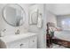 Modern bathroom featuring a sleek vanity with a round mirror, white countertops, and access to the bedroom at 9035 J M Keynes Dr # 33, Charlotte, NC 28262