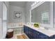 Elegant bathroom featuring double vanity, a framed mirror, and a soaking tub with tile surround at 105 Partridge Bluff Ne Dr, Concord, NC 28025
