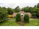 Inviting brick home features a lush front lawn with mature trees and a stone fountain at the base of the front steps at 105 Partridge Bluff Ne Dr, Concord, NC 28025