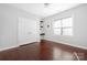 Minimalist bedroom with hardwood floors, a large window, a ceiling fan, and a built-in shelving unit at 16115 Chiltern Ln, Huntersville, NC 28078