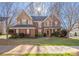 Charming two-story brick home with manicured lawn, complemented by mature trees and a welcoming front porch at 16115 Chiltern Ln, Huntersville, NC 28078
