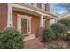 Exterior shot of a red brick home's front porch with a wood door and well-manicured landscaping at 16115 Chiltern Ln, Huntersville, NC 28078