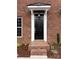 Inviting brick home featuring a black front door with a white frame and covered entrance and manicured landscaping at 447 Beacon Nw St, Concord, NC 28027