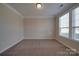 Empty bedroom showcasing neutral carpet, white trim, and a bright window overlooking outdoor greenery at 5017 Willing Ct # 124, Indian Land, SC 29707