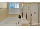 Relaxing bathroom with a large soaking tub, separate glass-enclosed shower, and plantation shutters at 8107 Crater Lake Dr, Indian Land, SC 29707