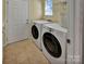Well-lit laundry room features tile floors, front loading washer and dryer, and a wire rack for storage at 8107 Crater Lake Dr, Indian Land, SC 29707