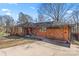 Charming red brick home featuring a spacious driveway, mature trees, and unique wooden garage doors at 851 Gist Rd, Rock Hill, SC 29732