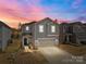 Charming gray two-story home featuring a two-car garage, landscaped yard at sunset at 2116 Belterra Dr, Charlotte, NC 28216