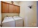 Bright laundry area featuring cabinets above a side-by-side washer and dryer set for convenient home laundry at 2316 Winding River Dr, Charlotte, NC 28214