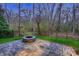 A stone patio features a built-in fire pit and a black fence with a view into the woods at 2835 Peverell Ln, Charlotte, NC 28270