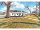 Quaint white house boasts a wrap-around porch and a well-manicured front yard with mature trees at 308 W First St, Lowell, NC 28098