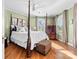 Serene bedroom featuring a four-poster bed, hardwood floors, and ample natural light at 308 W First St, Lowell, NC 28098