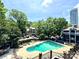 Community pool area featuring lounge chairs, mature trees, and a view of nearby city buildings at 433 W 8Th St, Charlotte, NC 28202