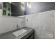 Contemporary powder room with stone textured walls, dark accent wall, and modern fixtures at 4335 Piper Glen Dr, Charlotte, NC 28277