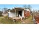 View of the back of the home, featuring a covered back porch with white railing and brick foundation at 4914 Ridgeley Dr, Charlotte, NC 28208