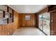 Cozy living room with natural wood paneling, built-in shelves, and sliding glass door to the backyard at 4914 Ridgeley Dr, Charlotte, NC 28208