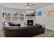 Inviting living room with a fireplace, a large sectional sofa, and large windows offering a view of the backyard at 5056 Blue Serenity Ct, Denver, NC 28037