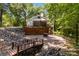 A blue home with a brick foundation, patio, fire pit, stone bridge, and creek at 601 Highland Forest Dr, Charlotte, NC 28270