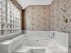 Bright bathroom with a large soaking tub, patterned wallpaper, and a privacy glass window at 6200 Summertree Ln, Charlotte, NC 28226