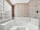 Close up of a bathtub featuring wallpaper and glass block windows at 6200 Summertree Ln, Charlotte, NC 28226