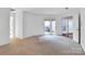 Open living room with neutral carpet, white walls, and access to a private balcony area at 6200 Summertree Ln, Charlotte, NC 28226
