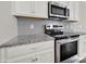 Kitchen featuring stainless steel microwave and oven, grey backsplash, and granite countertops at 769 River Park Rd, Belmont, NC 28012