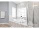 Bright bathroom featuring an oval soaking tub and glass-enclosed shower at 8504 Soaring Eagle Ln, Waxhaw, NC 28173