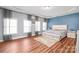 Bright main bedroom showcasing hardwood floors, tray ceilings, and a blue accent wall at 8504 Soaring Eagle Ln, Waxhaw, NC 28173