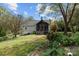 Backyard home view showcasing a screened-in porch, mature trees, and lush greenery at 10633 Hwy 52 Hwy, Rockwell, NC 28138