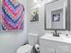 Bright bathroom featuring a white toilet, vanity with a modern sink, and colorful quilt hanging on the wall at 11416 Leadenhall Ln # 22, Charlotte, NC 28262