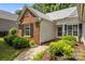 Close-up of home showcasing brick siding, dark shutters, and vibrant, green landscaping at 1286 Saint Katherines Way, Rock Hill, SC 29732