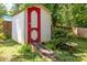 Charming backyard shed with a red door and wooden ramp nestled among lush greenery at 1286 Saint Katherines Way, Rock Hill, SC 29732