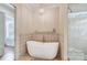 Bright bathroom featuring standalone tub with filler, decorative accent wall, and modern chandelier lighting at 215 Wesley Manor Dr, Matthews, NC 28104