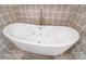 A modern, jetted soaking tub with mosaic tile surround and matte gold filler set on wood look tile flooring at 215 Wesley Manor Dr, Matthews, NC 28104