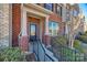 Close-up of a brick townhome entrance with a black door, white columns, and well-maintained landscaping at 2635 Winter Thistle Way, Indian Land, SC 29707