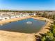 Wide aerial view of pond with fountain in a neighborhood community of townhomes and wooded landscape at 2635 Winter Thistle Way, Indian Land, SC 29707